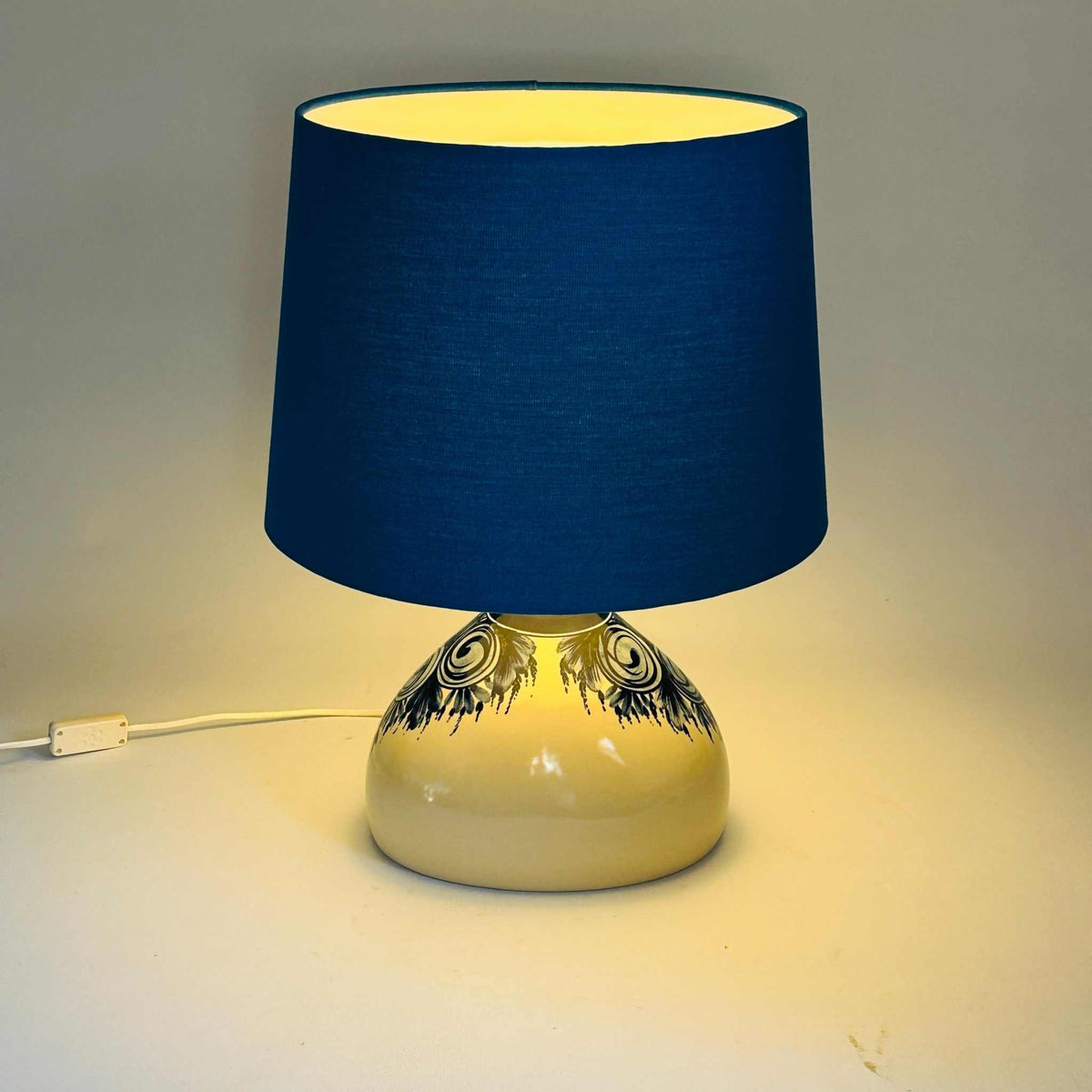 Lampe de table allumée, lumière chaude diffusée à travers l’abat-jour bleu