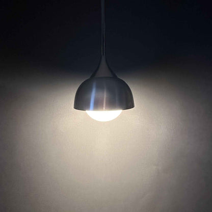 Staff Hängelampe vor dunklem Hintergrund mit warm leuchtendem Opalglasschirm und Aluminiumhaube
