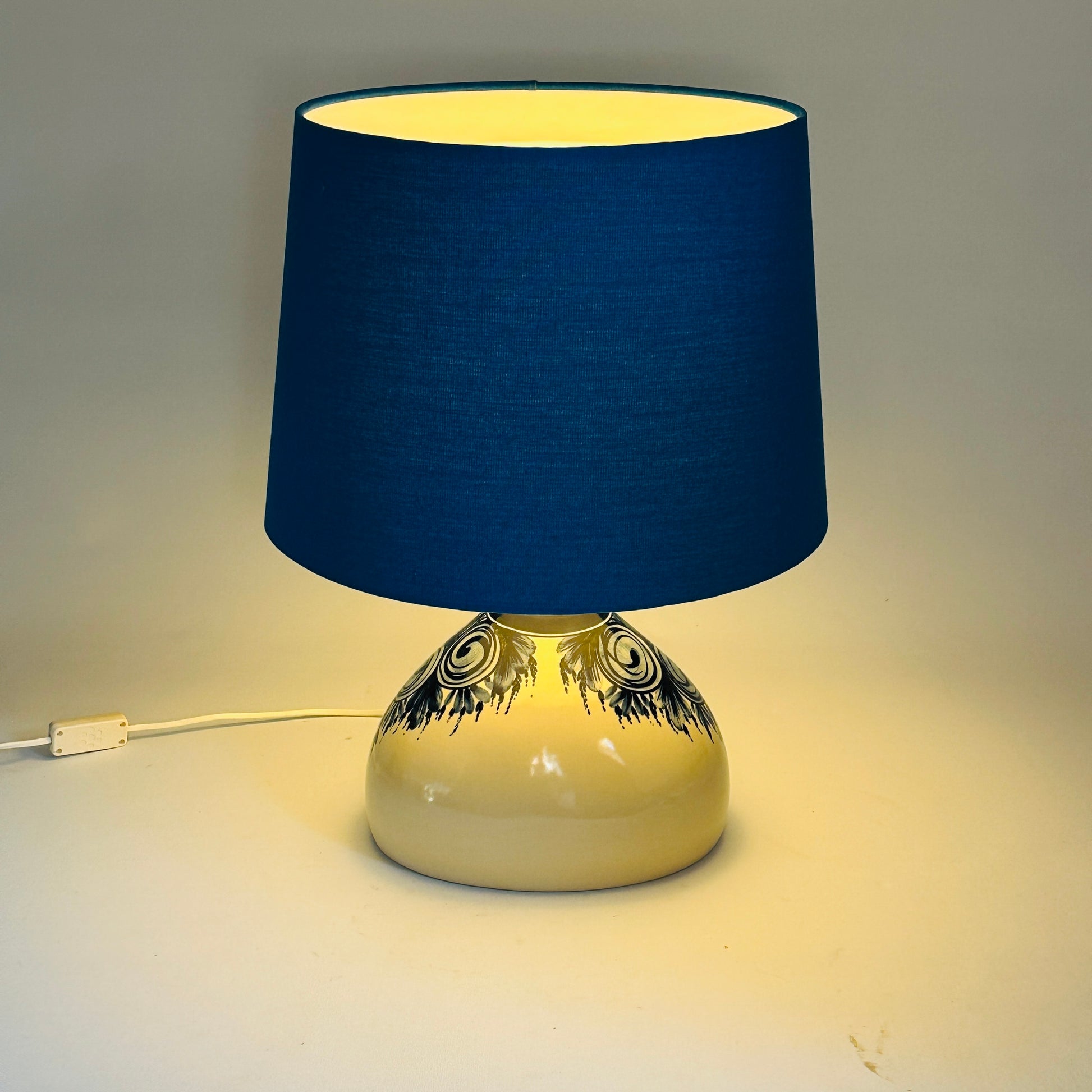 Tischlampe eingeschaltet, warmer Lichtschein durch den blauen Schirm