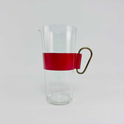 Gesamtansicht der klaren Carl-Auböck-Glaskaraffe mit roter Lederbanderole und Messinggriff aus den 1950ern