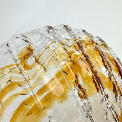 Detailansicht des gewellten Glasrands mit klaren und honigfarbenen Bereichen der Muschelschale