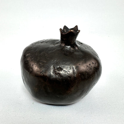 Schrägansicht der Granatapfel-Skulptur aus Bronze mit plastischer Krone und rauer Oberfläche