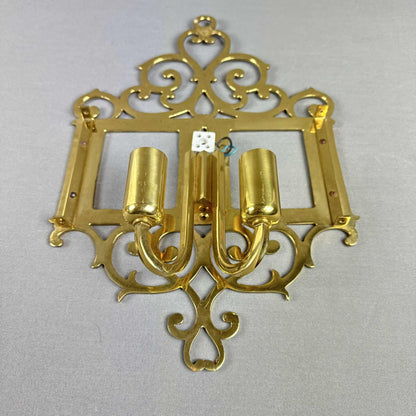 Rückansicht einer französischen Wandleuchte mit zwei Messingarmen und verspieltem Ornamentrahmen