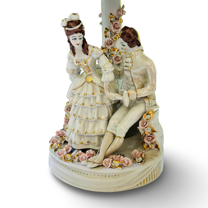 Nahansicht der Porzellanfiguren eines Paares mit rosa Blüten am Sockel der Apulum Leuchte aus den 1970ern