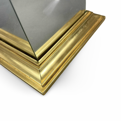 Nahaufnahme der gestuften goldfarbenen Sockelecke und des Spiegelglases der 1980er Säule