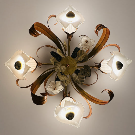 Eingeschaltete Florentiner Deckenleuchte an der Decke, warm leuchtende Calla-Glasschirme, Glasblüten und grüne Blätter um die gelbe Deckenrosette