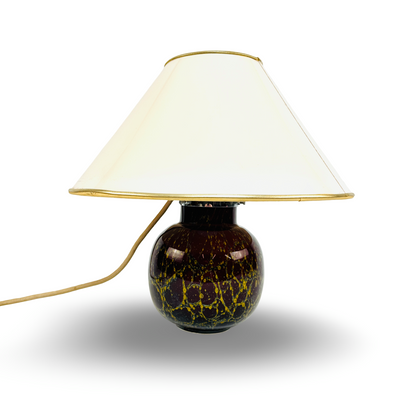 Frontansicht der unbeleuchteten Tischlampe mit hellem konischem Schirm und dunklem Ikora-Glasfuß