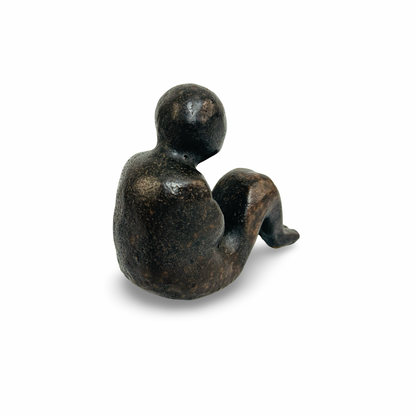 Seitliche Gesamtansicht der braunschwarzen Figur mit einem angezogenen Knie