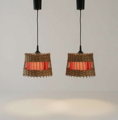 Zwei eingeschaltete Rattan-Pendelleuchten mit warm leuchtendem rotem Stoffkern