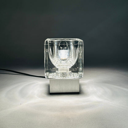 Kleine Gesamtansicht der eingeschalteten Peill & Putzler Glasleuchte mit reflektiertem Licht auf grauem Hintergrund