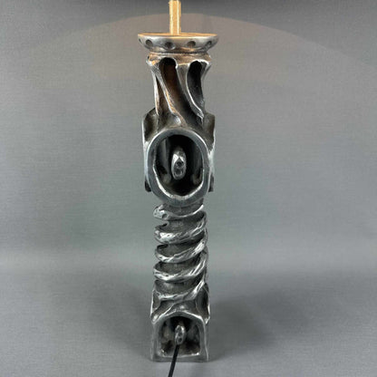Rückansicht des skulpturalen Metallfußes mit Durchbruchdekor und sichtbarem Kabel