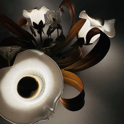 Eingeschaltete Calla-Glasschirme im Detail, warmes Licht und Schatten der Blattbänder an der Decke