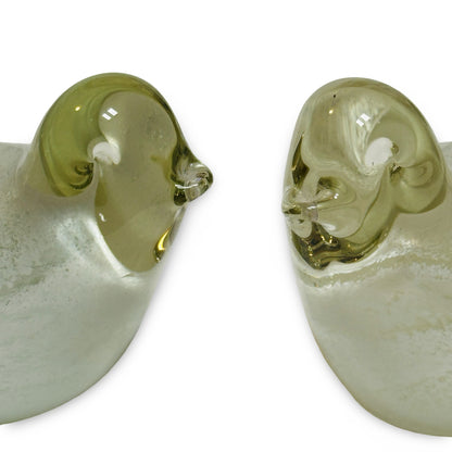 Close-up of both glass birds’ heads with pinched beaks and white glass eyes