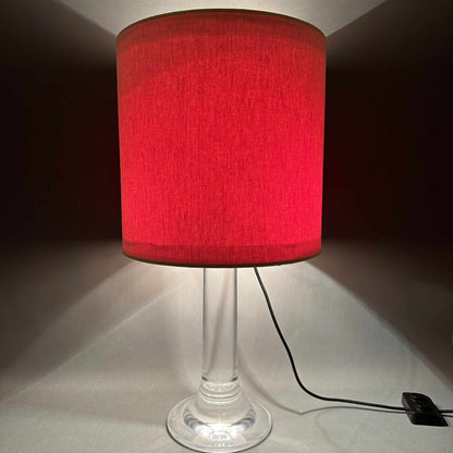 Eingeschaltete 70er Tisch- oder Bodenleuchte mit rotem Schirm und klarem Acrylfuß