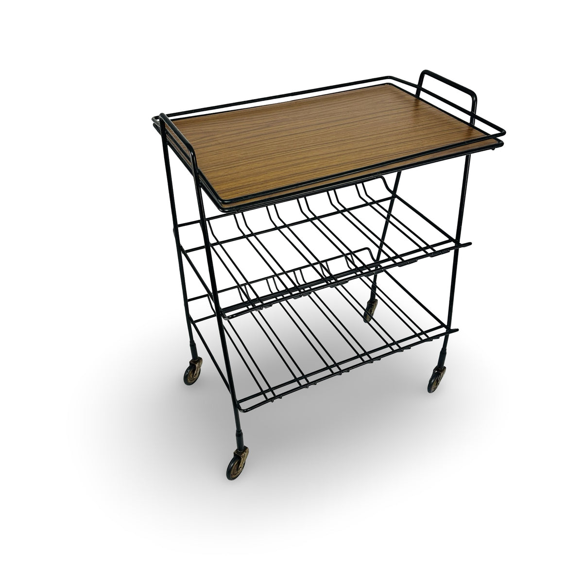 Vintage serving trolley in black plastic-coated wire with wood-grain tray and two wire racks, angled view on white