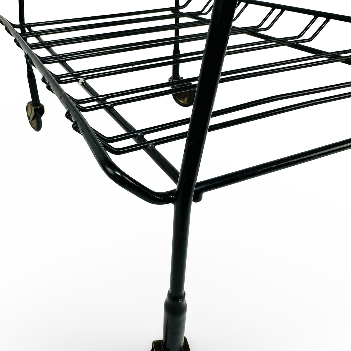 Detail of leg, sleeve and lower wire rack with brass castor in the background